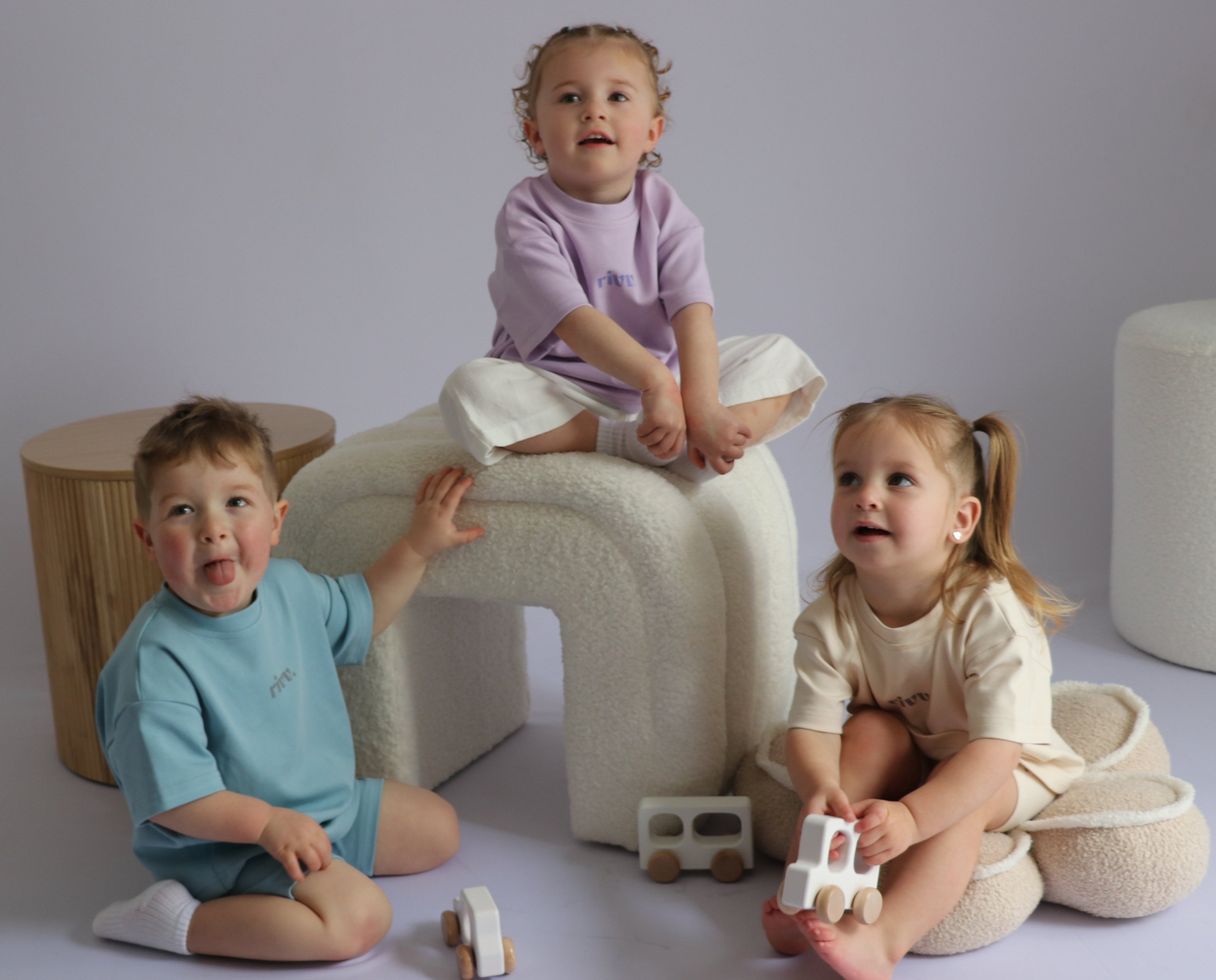 Three children playing with toys on a plain background