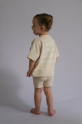 Child wearing a light-colored outfit with text on a plain background